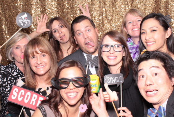 a photo of many wedding guests in a photo booth with a gold sequin backdrop