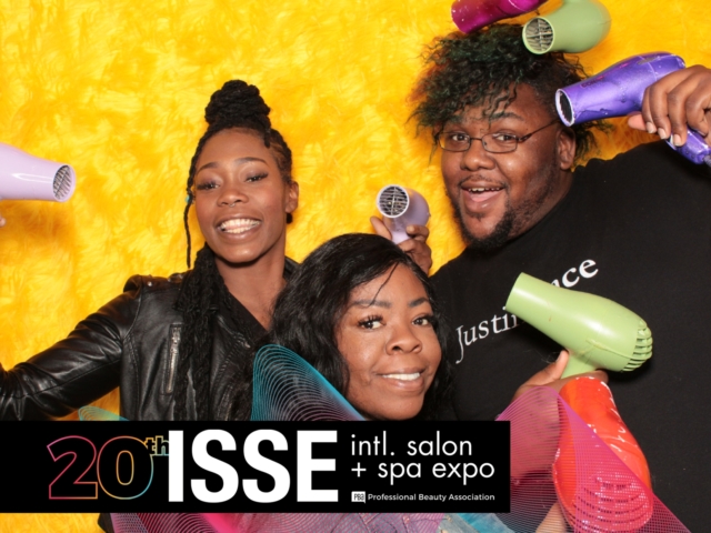 a photo booth photo with 3 guests taken on a yellow backdrop at the International Salon and Spa Expo 2019. Photo taken by photo booth los angeles rental company Maple Leaf Photo Booths